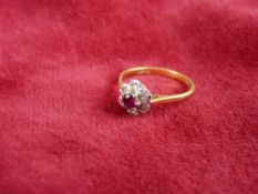 AN EIGHTEEN CARAT GOLD RUBY & DIAMOND CLUSTER RING having a centre ruby of visual estimate 0.35