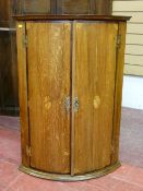 A 19th CENTURY OAK & CROSSBANDED MAHOGANY TWO DOOR BOW FRONT HANGING CORNER CUPBOARD with Sheraton