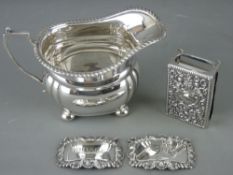 FOUR ITEMS OF SMALL SILVER to include a cream jug on ball feet, an embossed matchbox holder and