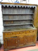 AN ANTIQUE OAK FARMHOUSE DRESSER having a three shelf canopied rack with decorative front frieze,