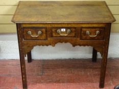 A GEORGE III CROSSBANDED OAK LOWBOY with three frieze drawers over a decorative apron, on canted