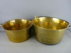 TWO LARGE ANTIQUE BRASS PRESERVE PANS with iron and brass swing handles, 36 and 31.5 cms diameters