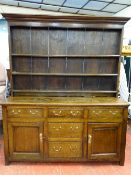 AN EARLY 19th CENTURY OAK DRESSER of joined construction with wide boarded three shelf rack over a