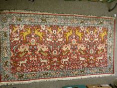 AN EXCELLENT INDIAN SILKWORK RUG, red ground with a repeating pattern of wild beasts, animals and