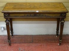 A VICTORIAN EMPIRE STYLE WALNUT FOLDOVER TOP CARD TABLE having a baize lined interior, carved frieze