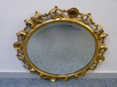 A VINTAGE CARVED GILT WOOD & GESSO FRAMED CIRCULAR WALL MIRROR with pierced foliate design (some