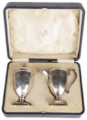 A George V cased silver sifter and cream jug, hallmarked Birmingham 1925