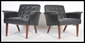 A pair of vintage danish influence mid 20th century, circa 1960's black faux leather armchairs.