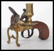 A good copy of a brass flintlock tinder lighter, scroll engraved frame with lyre stand and turned