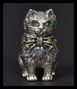 A sterling silver miniature figurine of a cat having emerald inset eyes. Weighs 17 grams.