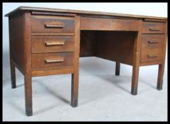 A mid century Air Ministry style oak twin pedestal desk raised on squared legs with a series of