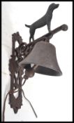 A vintage cast iron wall mounted bell in the form a standing black dog. Measures 35 cm high.