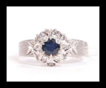 A hallmarked 18ct white gold sapphire and diamond ring having a central dark blue sapphire with a