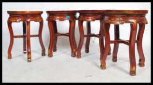 A set of four 20th century Chinese oriental stools having round tops and carved scrolls with x-frame