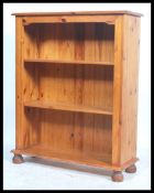 An antique style 20th century pine open window bookcase cabinet raised on bun feet with flared