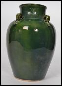 An early 20th century tall vase / water carrier in a vibrant green glaze, four string holes to the