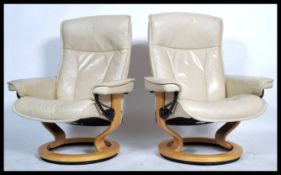 A pair of cream leather Ekornes Stressless reclining armchairs being upholstered in cream leather