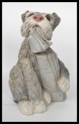 A 20th century stone dog figurine modelled with chewed newspaper in mouth. Measures 31 cm high.