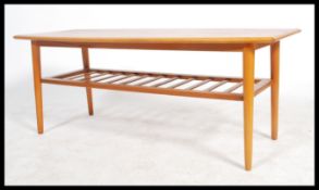 A retro 20th century teak wood surfboard style coffee table being raised on shaped tapering legs