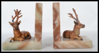 A pair of early 20th century vintage bookends in the form of cold painted cast metal stags raised on