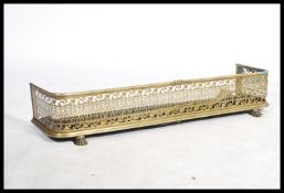 A 19th century brass fire fender of grille form having a pierced scrolled decoration having hairy