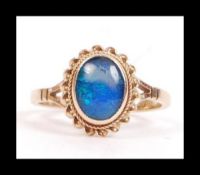 A hallmarked 9ct gold and opal style ring with a single opal doublet in a bezel setting.