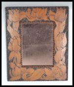 An early 20th century pokerwork mirror having a central peach glass inset mirror with Art Nouveau