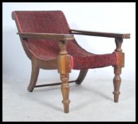 A 20th Century Plantation chair / armchair with 2 slide out arms being raise on turned legs with