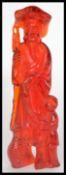 A 20th century red resin Chinese figurine of a fisherman giving a carp to a boy. Please see