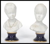 A pair of Unter Weiss Bach 1882 ceramic bust figurines of children - girl and boy raised on cobalt