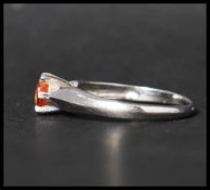A hallmarked 9ct white gold solitaire ring set with a single round cut orange stone. Hallmarked