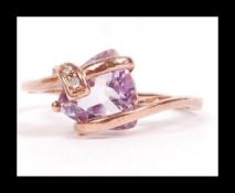 A 9ct rose gold ring set with a large purple stone with diamond accents in a contemporary setting.