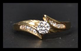 A 14ct gold and diamond crossover ring having a central prong set diamond with 8 diamonds to the