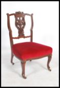 An Edwardian mahogany nursing chair having a pierced vase back with overstuffed seat raised on