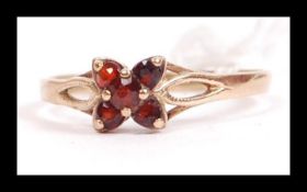 A hallmarked 9ct gold and garnet cluster ring having pierced shoulders. Hallmarked Edinburgh. Weight