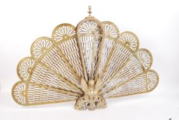 A vintage early 20th century peacock fan fire guard having fold out brass fan sections