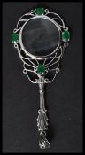 A silver magnifying glass having emerald cabochons with acanthus leaf handle. Weighs 18 grams.
