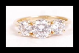 A 14ct gold and CZ trilogy ring set with 3 bright round cut CZ with bezel set CZ in heart accents to