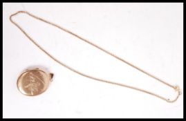 A 9t gold box lined necklace chain and large oval locket with chased decorated swan and reeds facia.