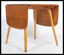 A mid 20th Century Ercol drop leaf dining table with elm top raised on beechwood base. Measures 72cm
