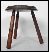 A 19th century carved oak spinning stool raised on tripod legs with carved floral medallion to the