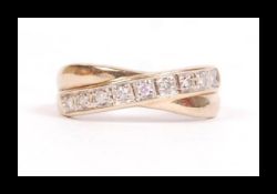 A hallmarked 9ct gold and diamond band crossover ring set with 9 x 2pt diamonds. Hallmarked