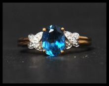 A hallmarked 9ct gold diamond and topaz ring having a central oval cut blue topaz flanked by diamond