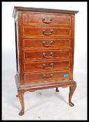 An Edwardian mahogany inlaid pedestal music cabinet being raised on cabriole legs with upright