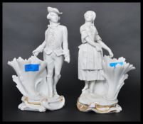 A pair of 19th century parian ware figurines of a dandy gent and a maiden raised on cornucopia spill