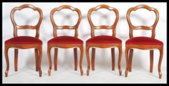 A set of four 20th century Victorian style mahogany balloon back dining chairs having overstuffed