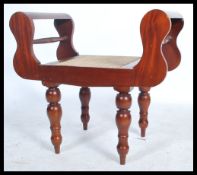 A Regency revival 20th century double scroll arm mahogany window seat, raised on turned legs with