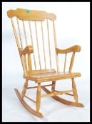 A 20th century beech farmhouse rocking chair with spindle back, scroll arms and solid seat base.
