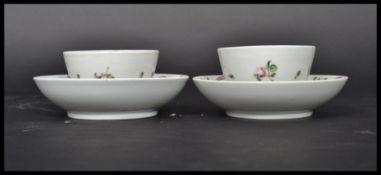 A pair of 18th century English tea bowls and saucers painted with pink ribbon and floral sprays.