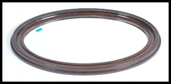 An early 20th century faux rosewood framed oval mirror having a central bevelled glass mirror